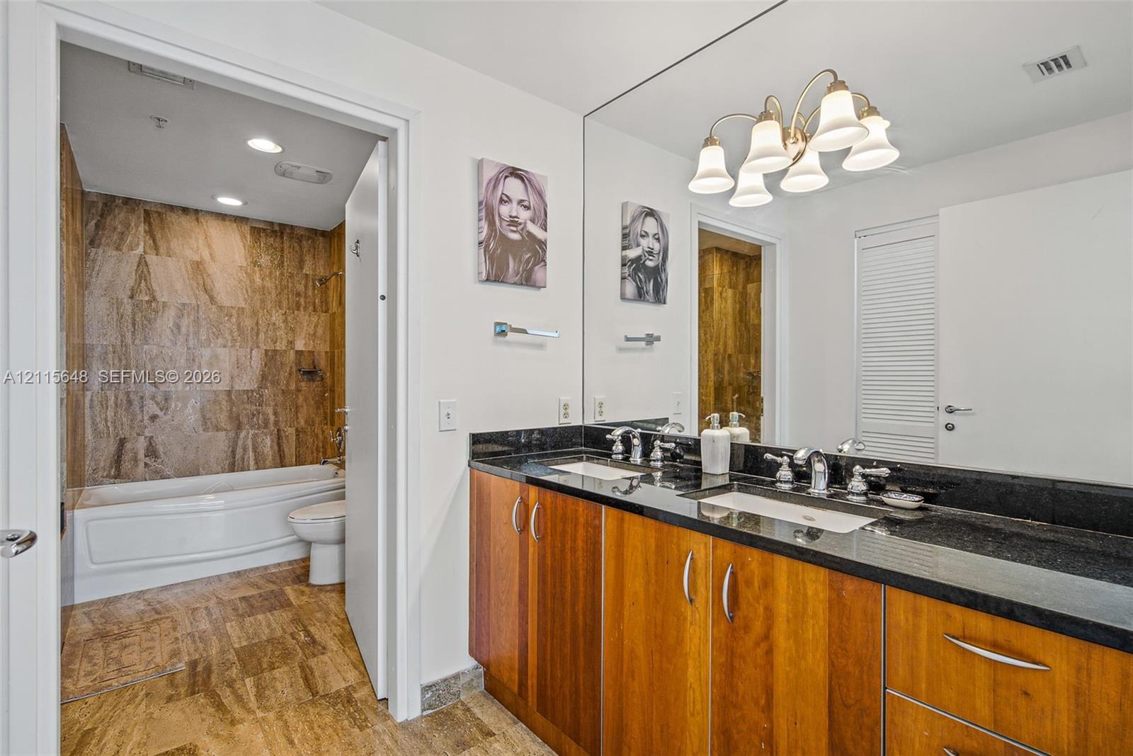 Dual-vanity cabinet with stone countertop, drop-in rectangular sinks, and multi-light vanity fixture