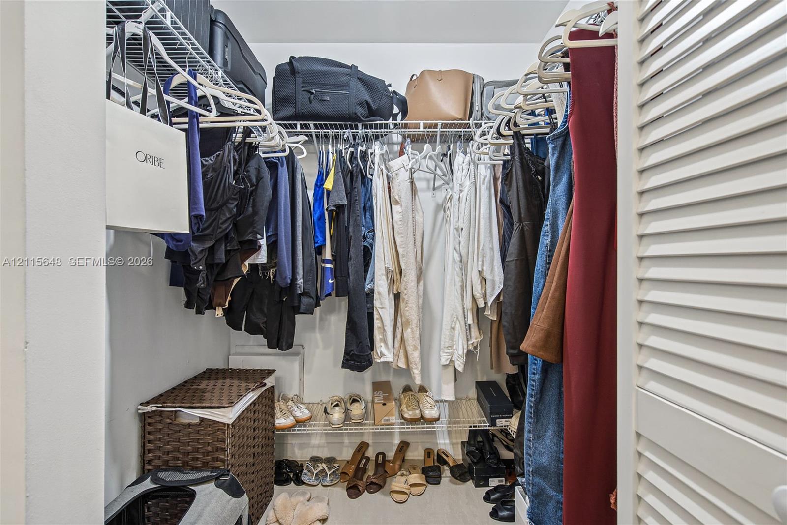 Walk-in closet featuring tiered wire shelving, double-hanging rods, and white louvered doors