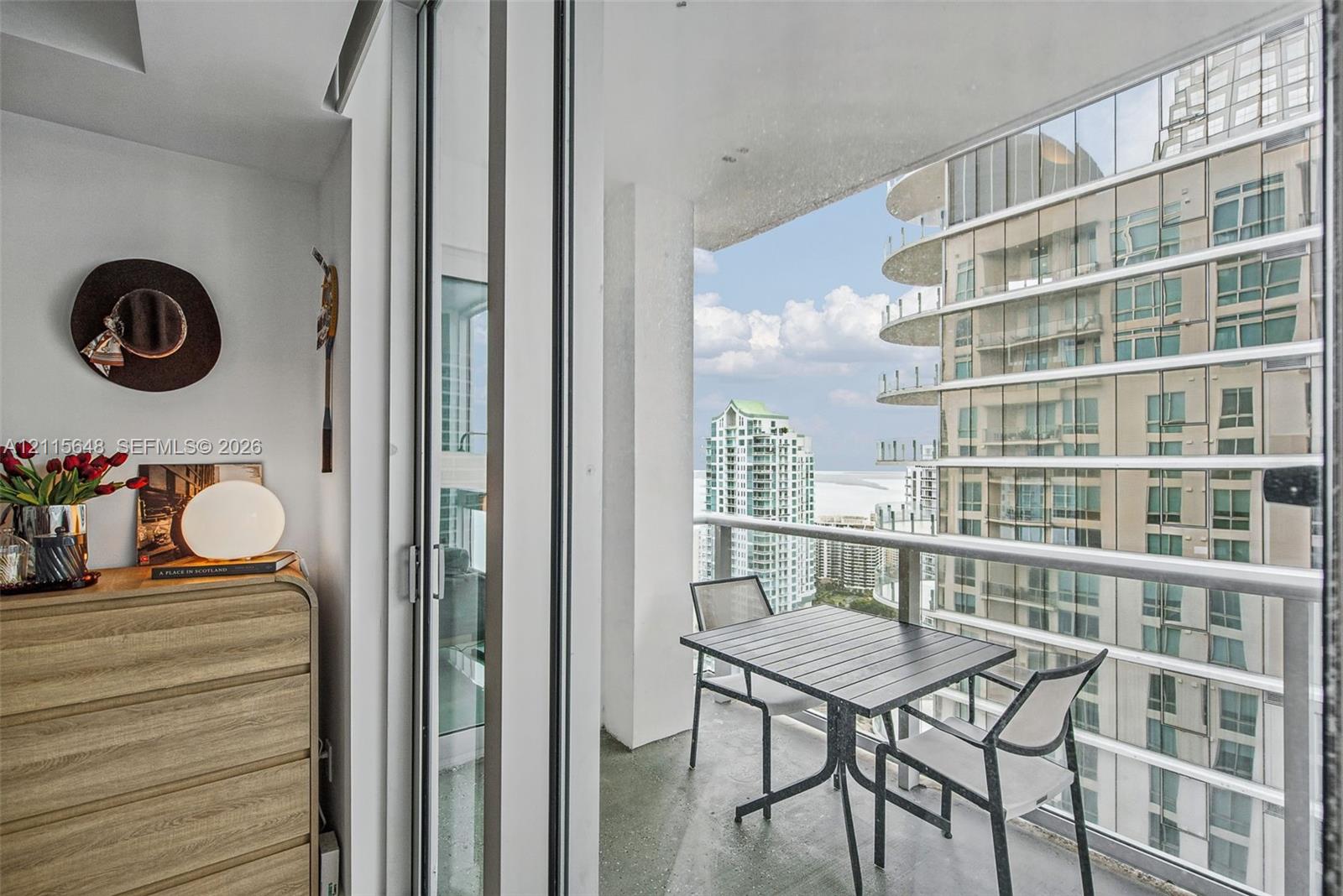 Private balcony featuring floor-to-ceiling glass sliding doors, a metal railing, and concrete flooring