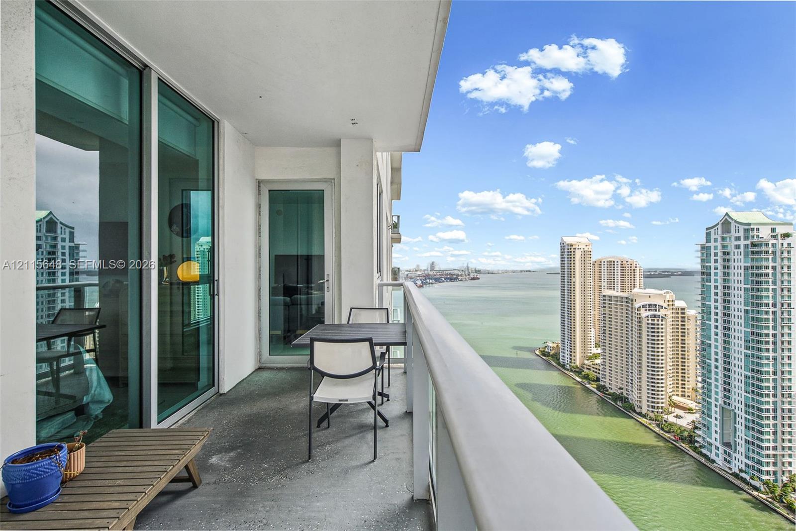 Covered balcony featuring expansive glass sliding doors, concrete flooring, and a metal railing
