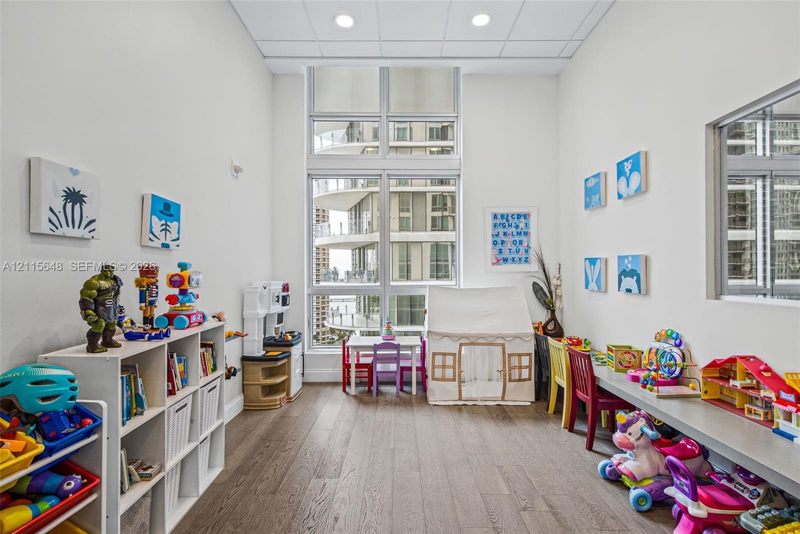 Room featuring wood-finish flooring, floor-to-ceiling windows, and recessed lighting