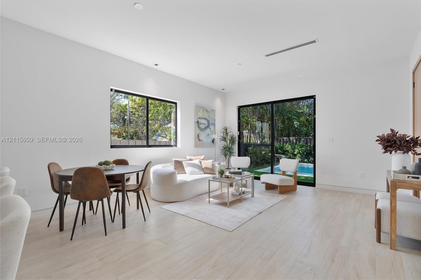Light-filled living area featuring wood-finish flooring, recessed lighting, and expansive glass sliding doors
