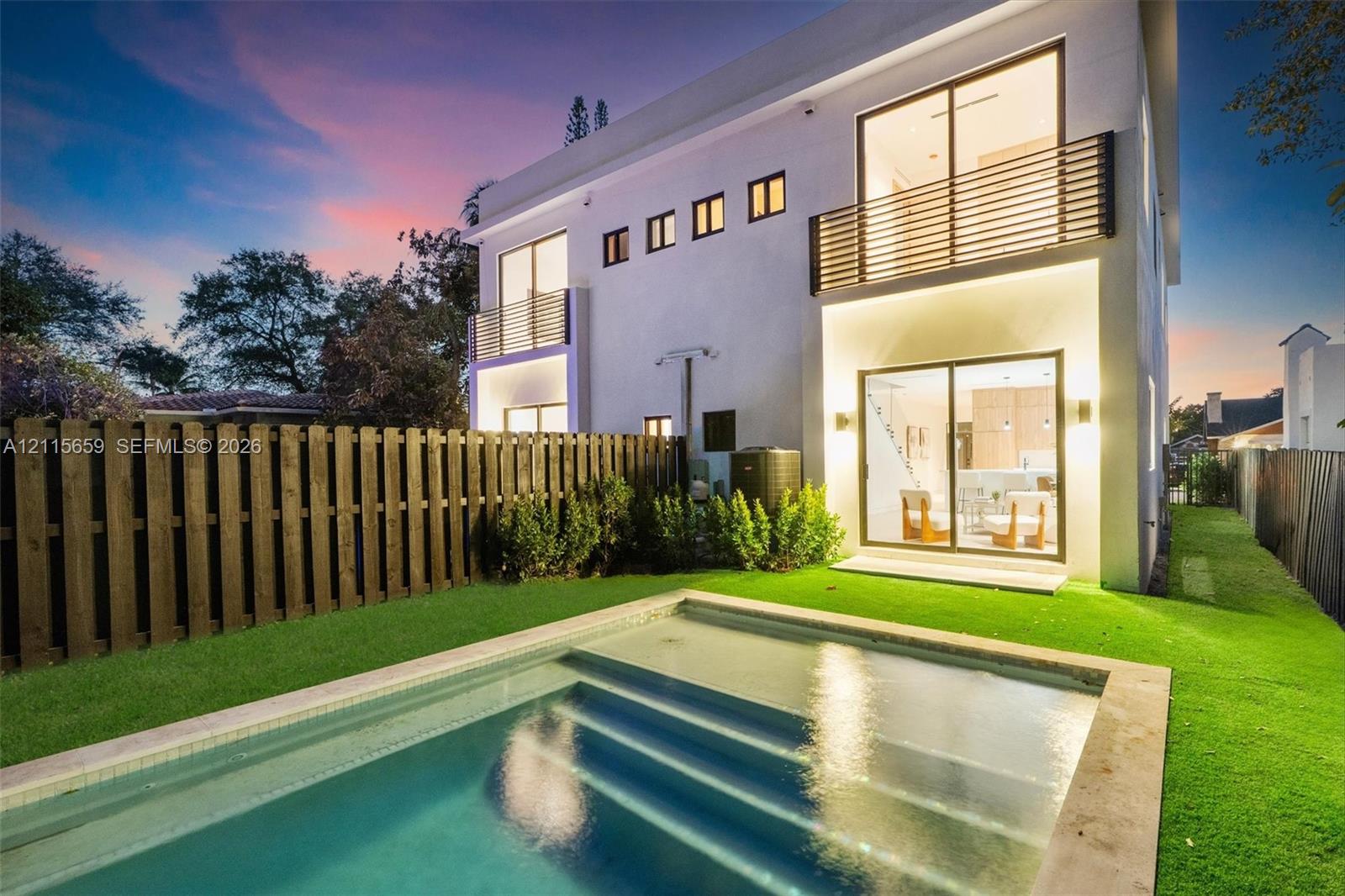 Two-story exterior with stucco finish, in-ground swimming pool, horizontal slat balcony railings, sliding glass doors, and privacy fencing Two-story exterior with stucco finish, in-ground swimming pool, horizontal slat balcony railings, sliding glass doors, and privacy fencing