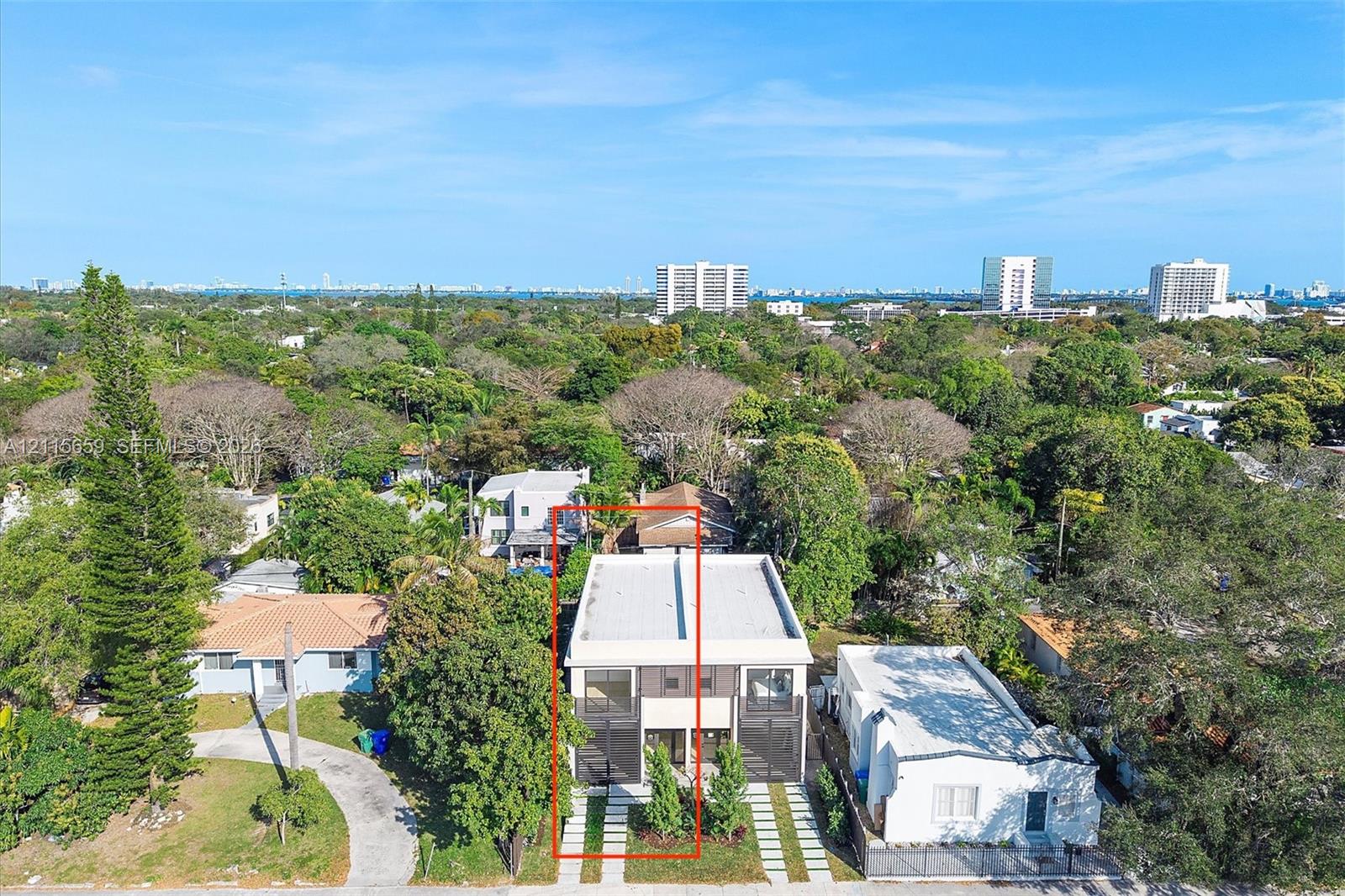Two-story residence featuring a flat roofline, multi-level balconies, large glass sliding doors, and a paver-style driveway