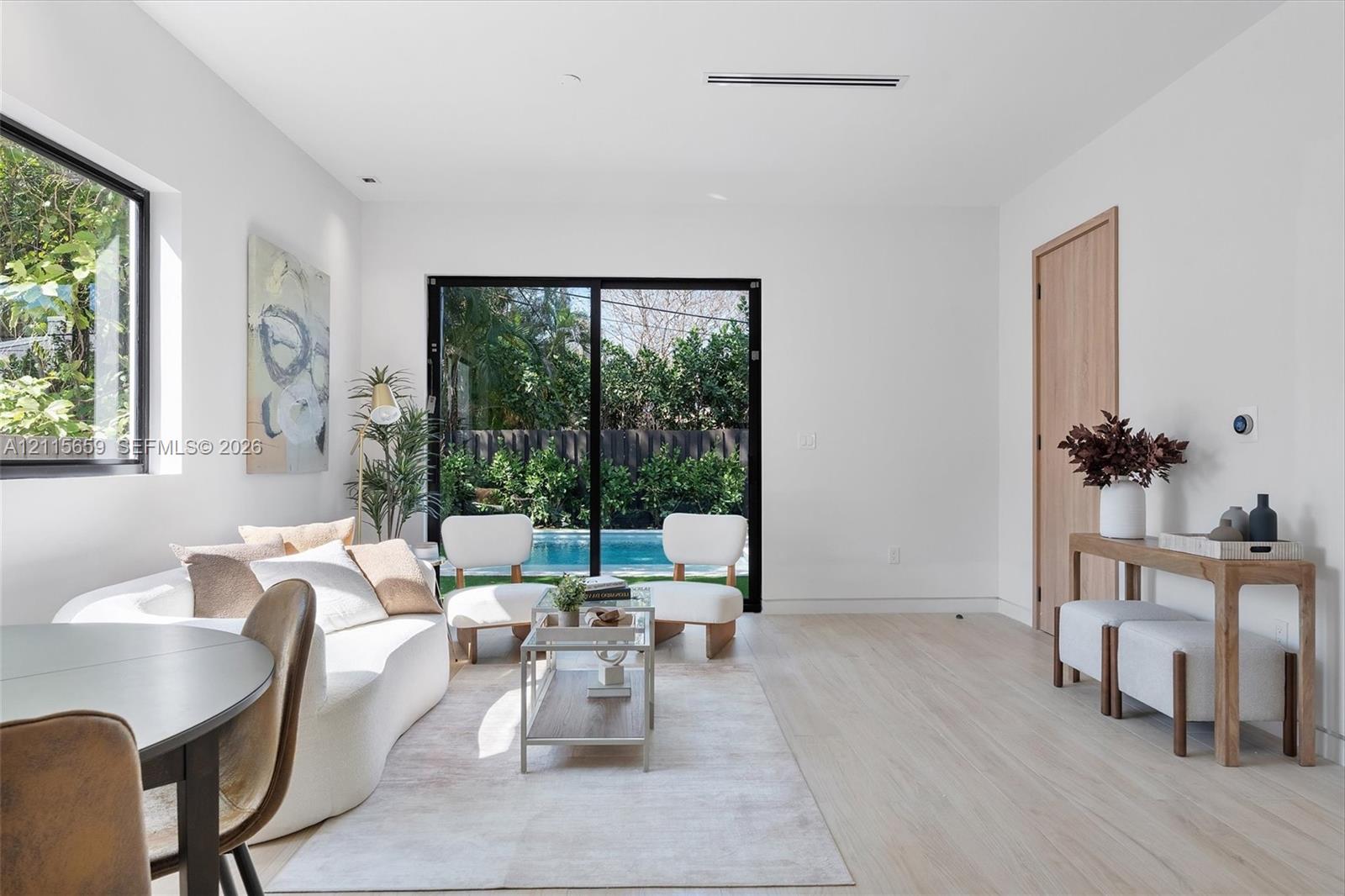 Open-concept interior featuring light wood-finish flooring, sliding glass patio doors, recessed ceiling lighting, and natural wood-tone interior doors