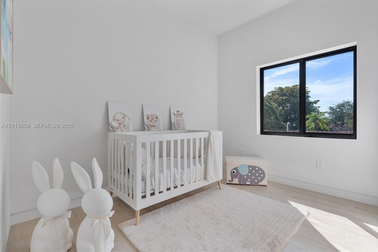 Bright room featuring neutral wall tones, wood-finish flooring, and a large window with a black frame