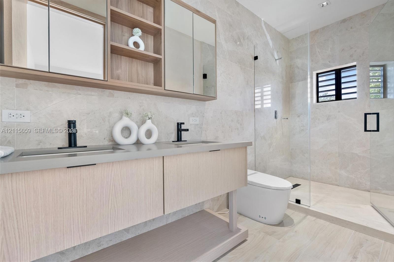 Floating vanity with integrated sinks, wood-finish cabinetry, matte black faucets, and full-height stone wall tile