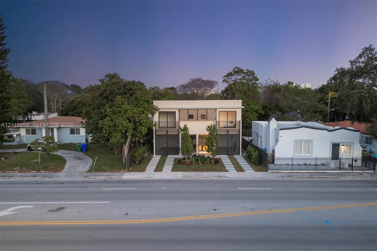 Modern two-story exterior featuring a clean facade, glass-paneled balconies, dual concrete-paver driveways, and geometric architectural design