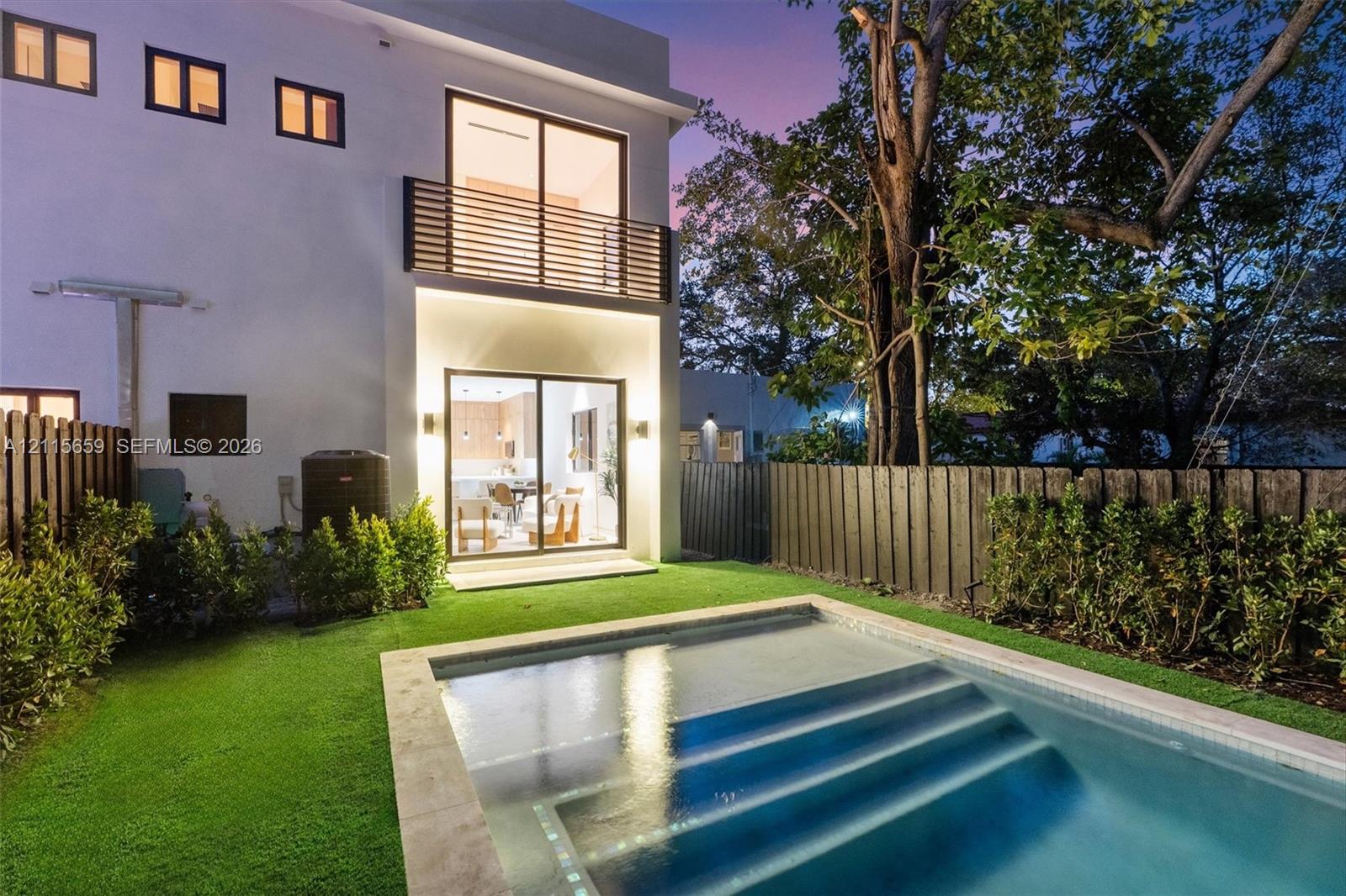 Modern exterior featuring a swimming pool with integrated stairs, synthetic lawn, wood-slat upper balcony railing, and floor-to-ceiling sliding glass doors