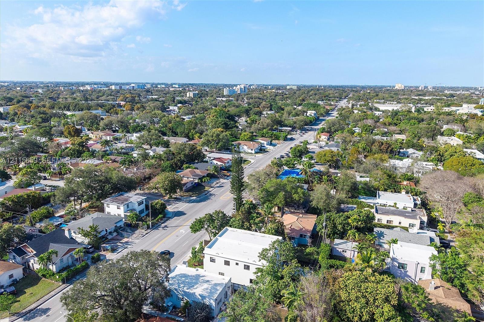 Aerial perspective of an established neighborhood featuring mature tree canopy, varied residential density, paved thoroughfares, and proximity to regional infrastructure