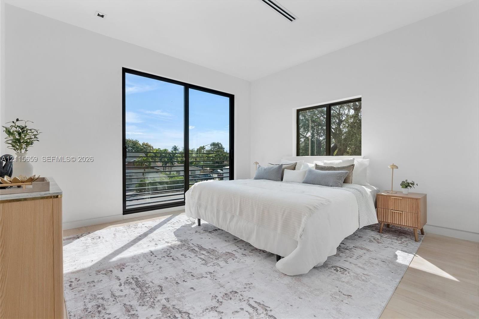 Floor-to-ceiling black-framed sliding glass door with a balcony railing, neutral-toned walls, wood-finish flooring, and recessed ceiling lighting