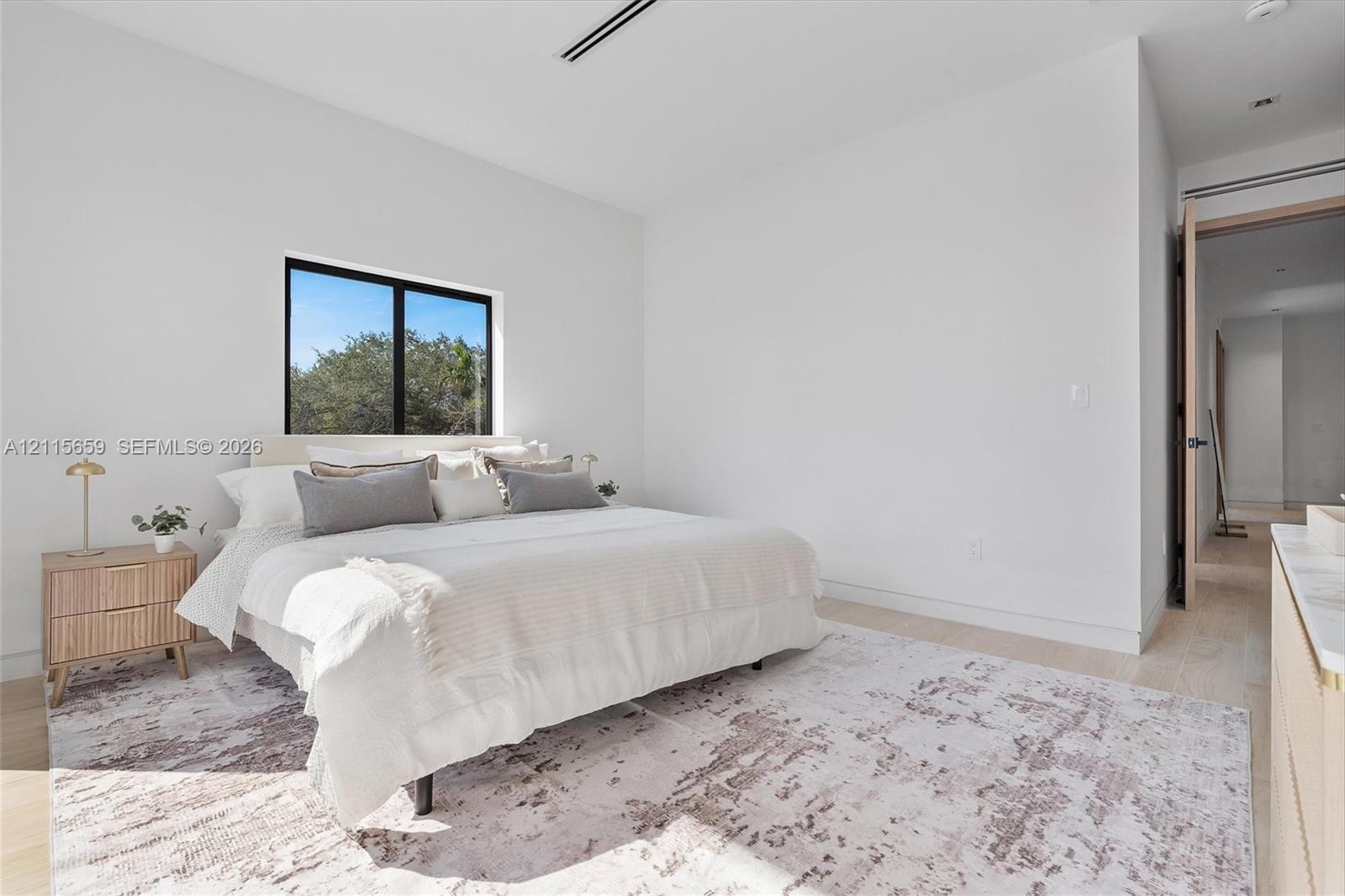 Neutral-toned room featuring wood-finish flooring, recessed ceiling lighting, and a window with a black frame