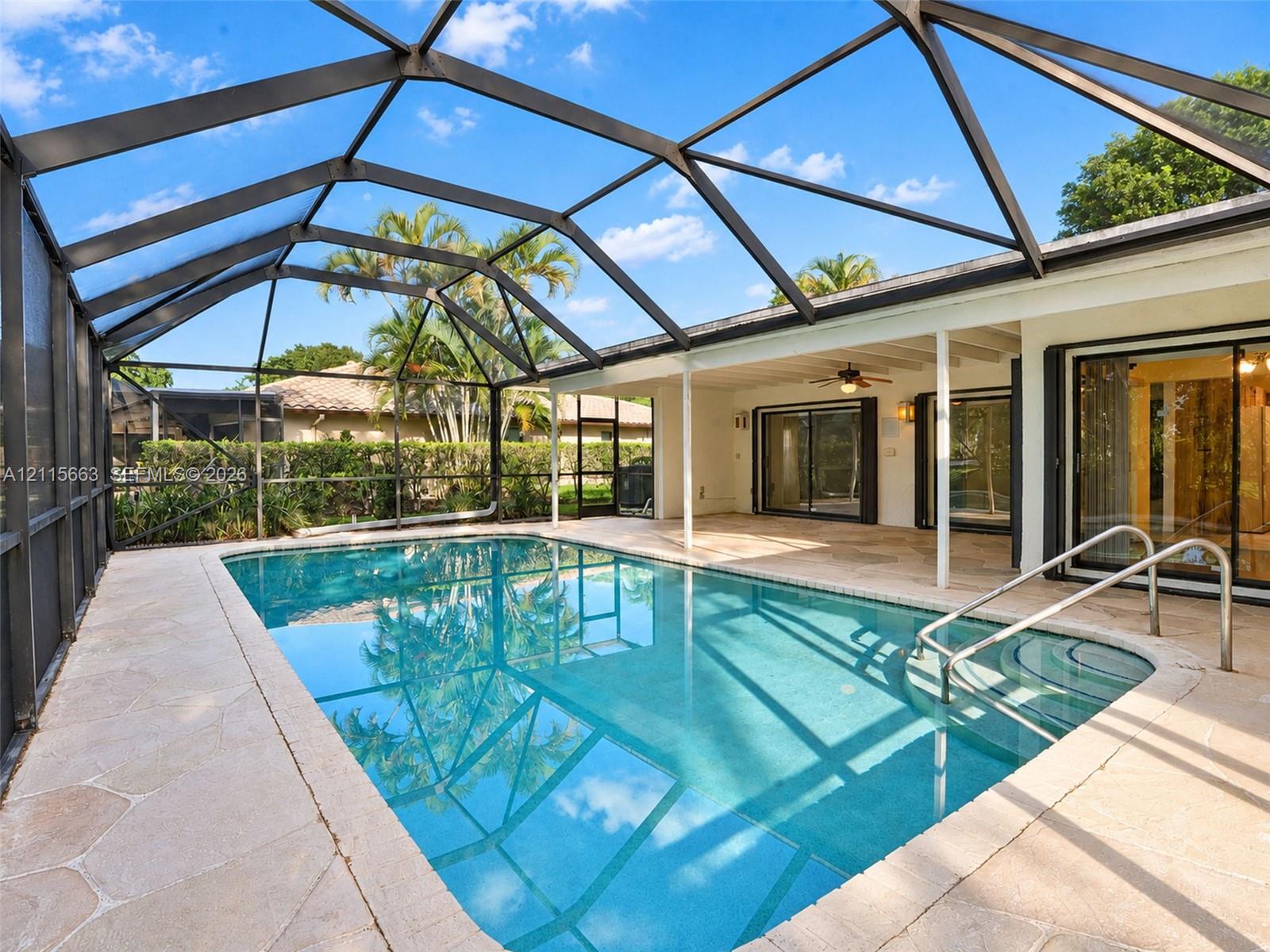 Screen-enclosed swimming pool with stone-finish paver deck and built-in steps