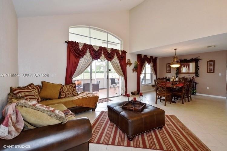 Vaulted ceilings, expansive arched windows, sliding glass doors, and light-tone tile flooring