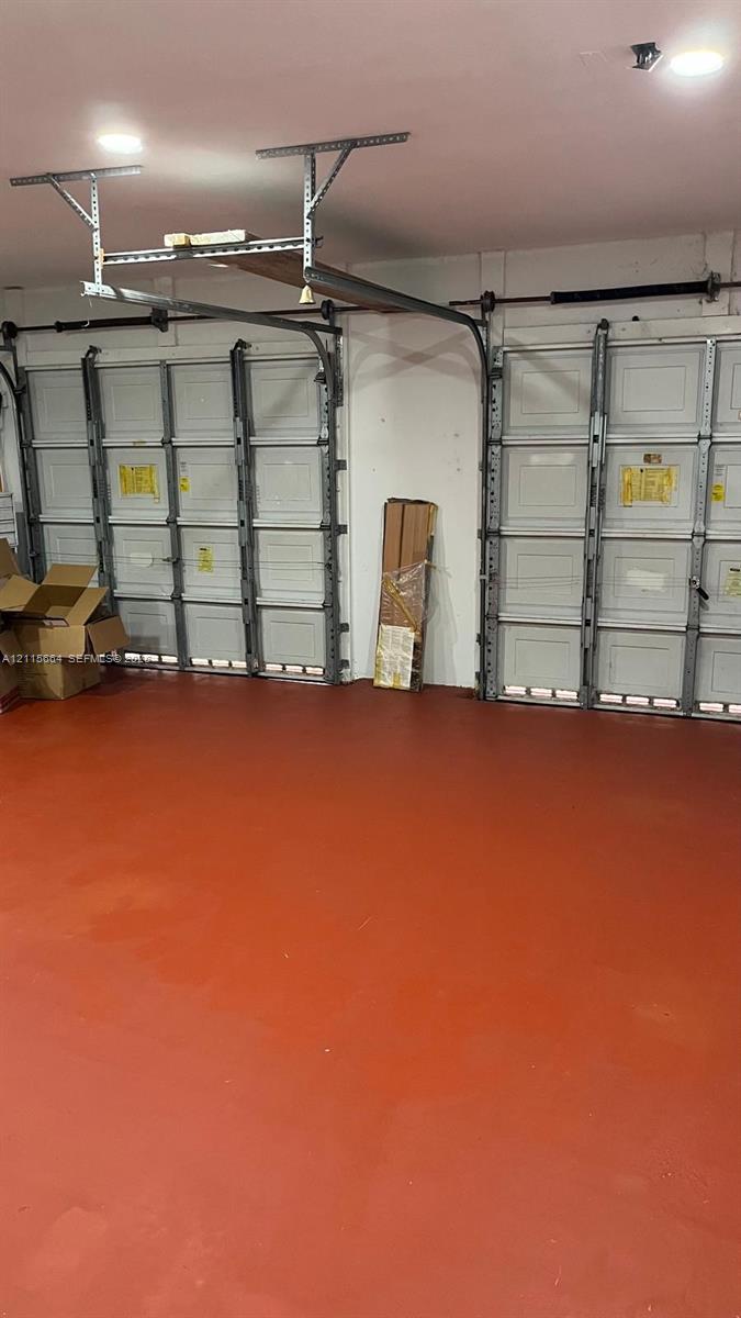 Two-car garage featuring finished concrete flooring, recessed lighting, and dual sectional metal garage doors with overhead tracking systems
