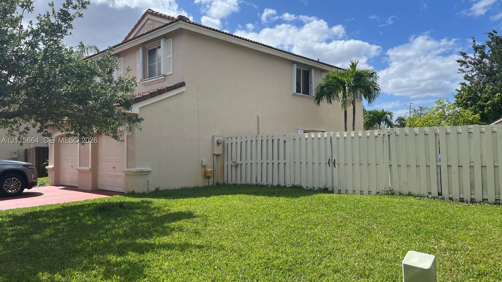 Two-story exterior featuring a stucco finish, tile roof, attached two-car garage, and fenced private yard