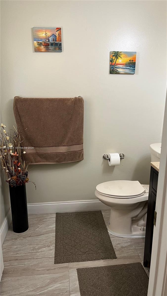 Porcelain tile flooring, standard-height toilet, and mounted toilet paper holder