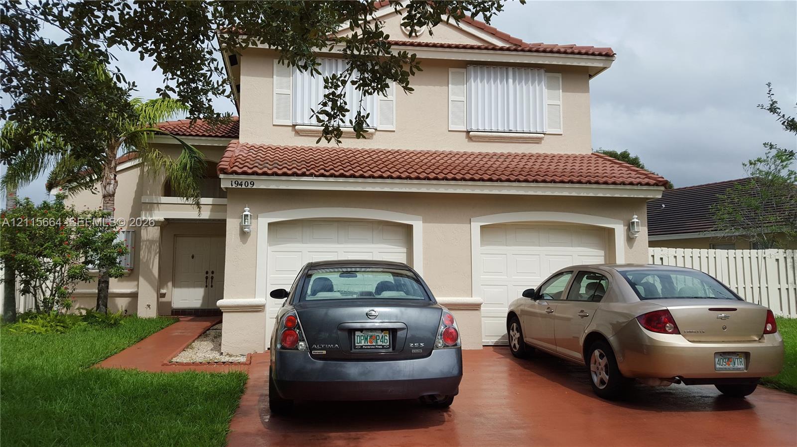 Two-story exterior featuring a tile roof, stucco finish, and a two-car garage