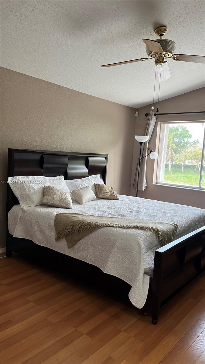Vaulted ceilings, wood-finish flooring, and a multi-blade ceiling fan with integrated lighting