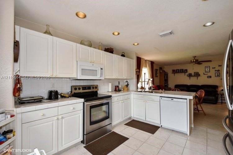Kitchen featuring white cabinetry, tile countertops, recessed lighting, and stainless steel appliances