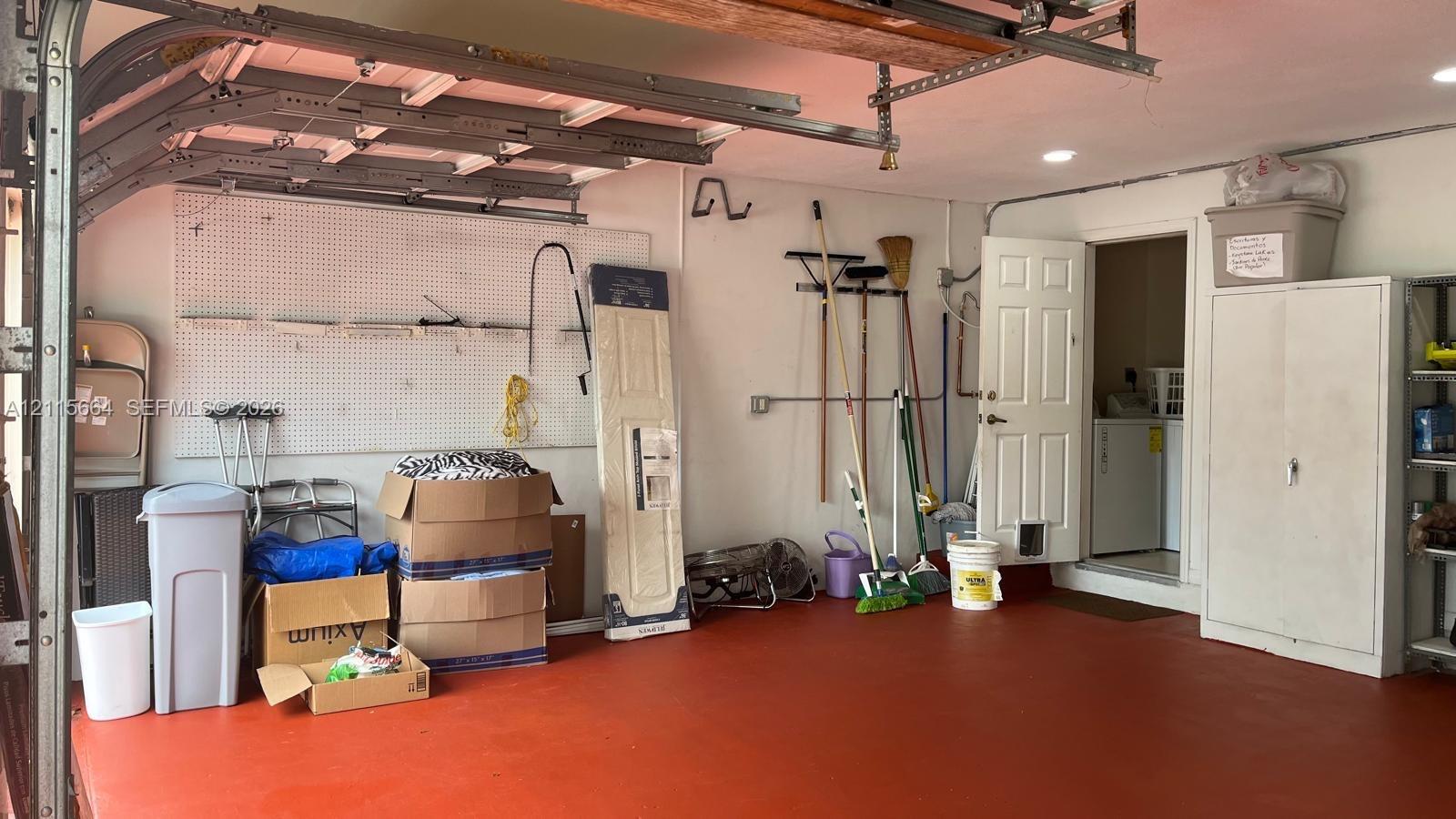 Attached garage featuring recessed lighting, a painted floor surface, mounted pegboard wall organizers, and a metal storage cabinet