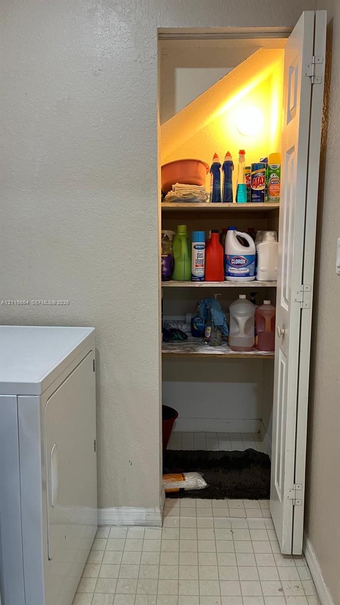Storage closet featuring three levels of built-in shelving, white bi-fold door, and light fixture