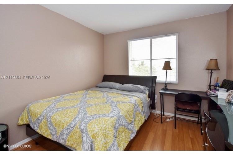 Neutral wall tones, wood-finish flooring, and a large window featuring horizontal blinds