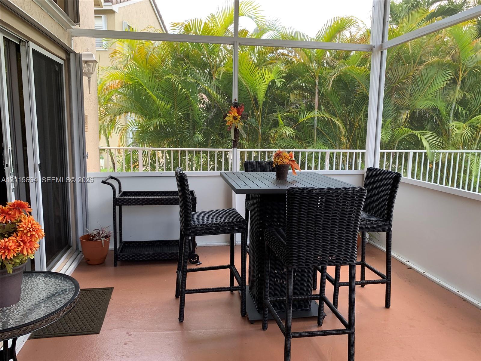 Screened-in balcony featuring painted concrete flooring, white metal railing, and aluminum enclosure