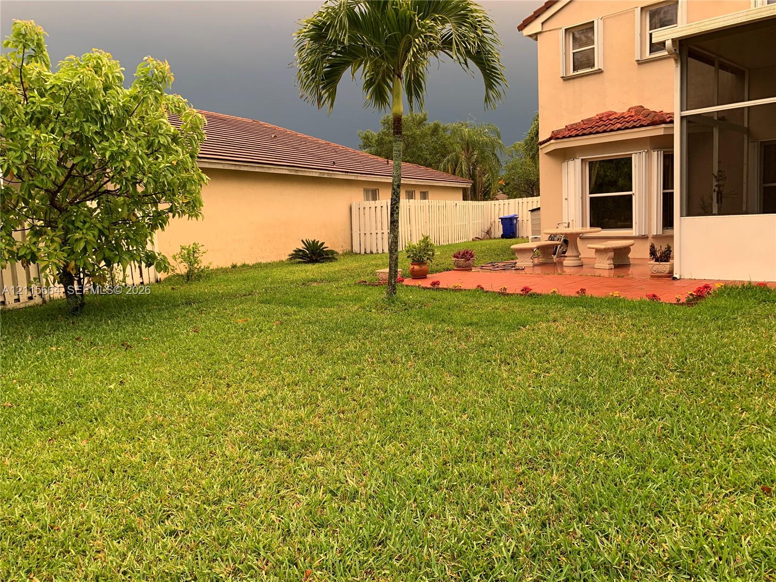 Backyard featuring a concrete paver patio, a screened enclosure, and perimeter white vinyl fencing