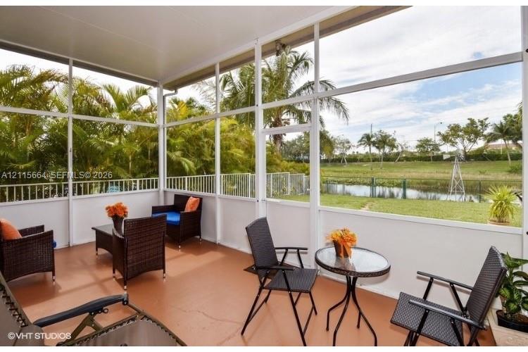Screened-in lanai featuring a solid roof, concrete flooring, and metal frame enclosure overlooking a grassed exterior space with water frontage and mature landscaping