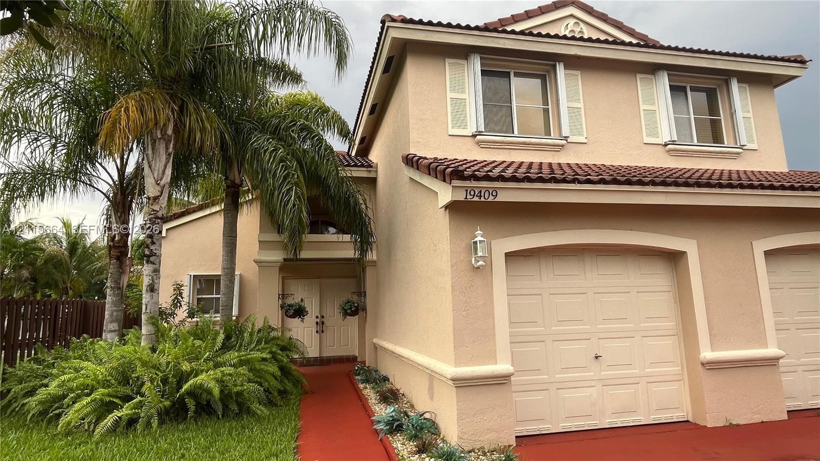 Two-story stucco exterior featuring a multi-gabled tile roof, double-entry front doors, a multi-car garage, and mature palm landscaping