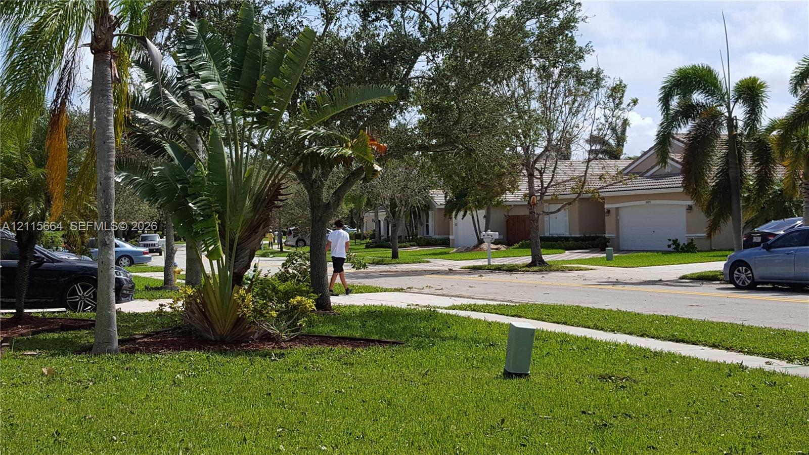 Single-story exterior featuring a hip roof, stucco siding, and an attached two-car garage, surrounded by landscaped grounds with mature palm trees