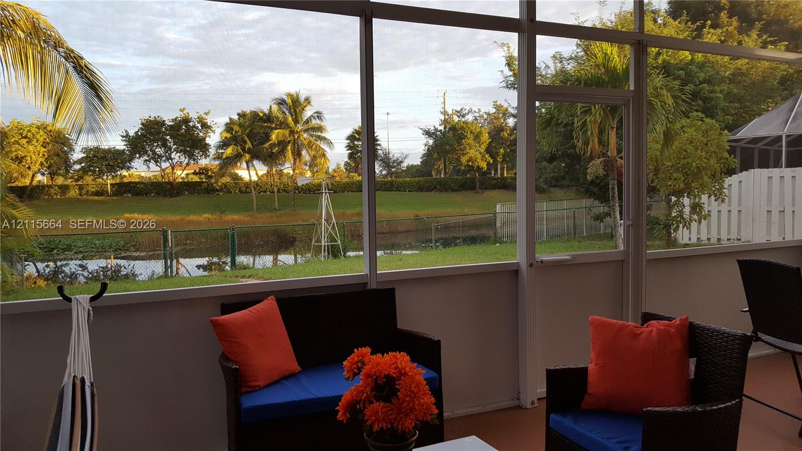 Screened lanai featuring a solid-panel knee wall, aluminum frame construction, and direct exposure to a pond
