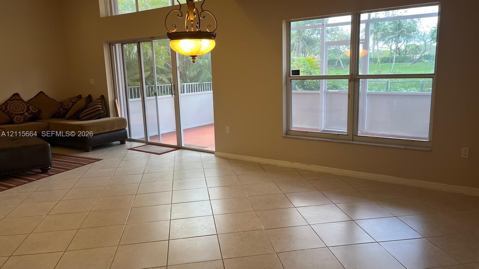 Large-format neutral tile flooring, vaulted ceilings, dual-pane windows, and a sliding glass door providing access to a screened-in lanai