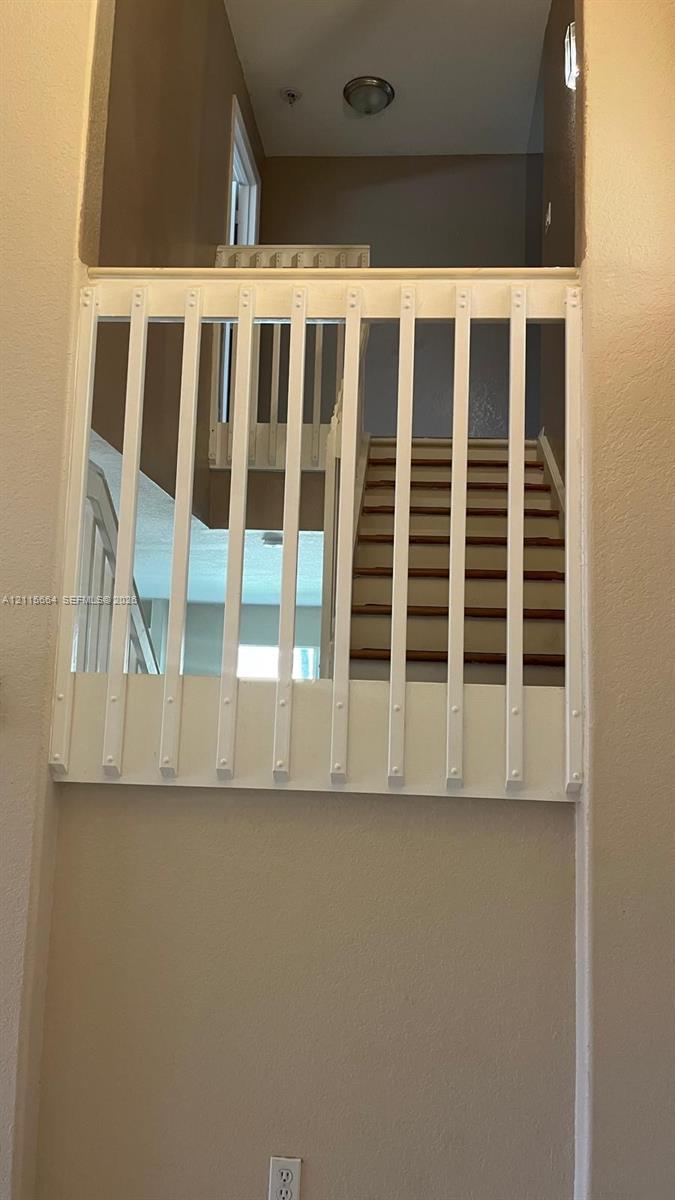 Interior overlook featuring a white vertical balustrade, wood-finish stair treads, and a flush-mount ceiling fixture