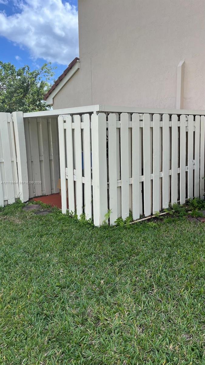 Exterior storage area enclosed by a white wood-picket fence
