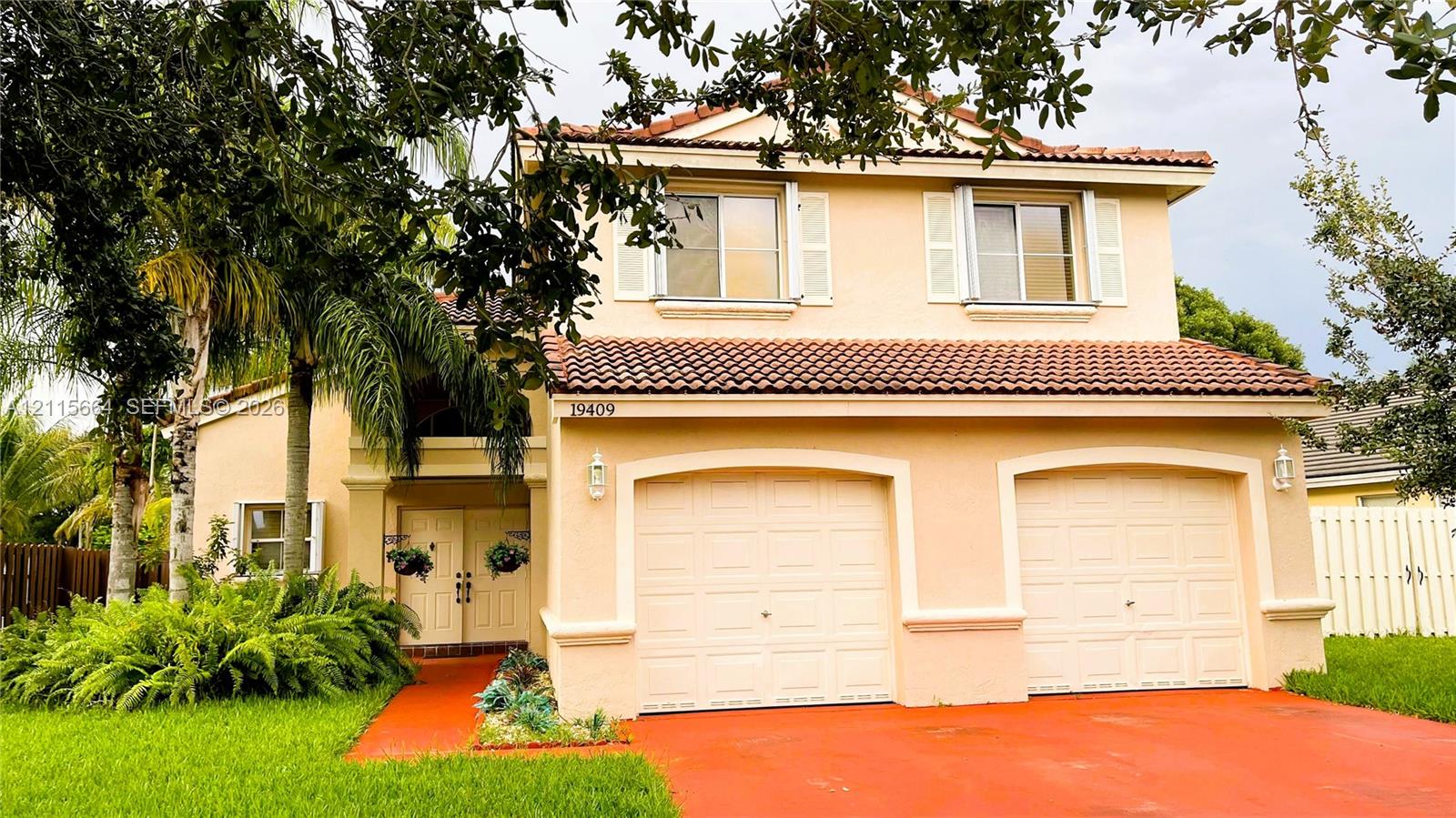 Two-story exterior featuring a stucco facade, dual-bay garage, tiled roof, and double-door entryway Two-story exterior featuring a stucco facade, dual-bay garage, tiled roof, and double-door entryway