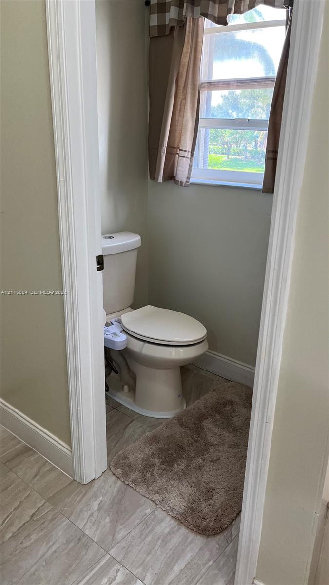 Neutral-toned bathroom featuring tile flooring and an exterior window