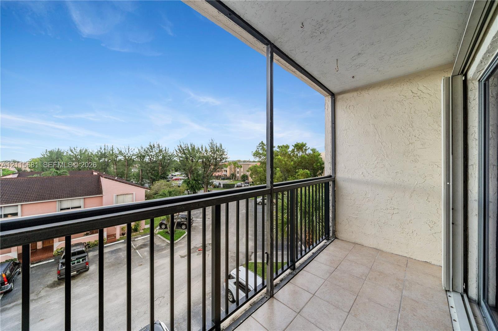Covered balcony featuring a screen enclosure, metal railings, and tile flooring