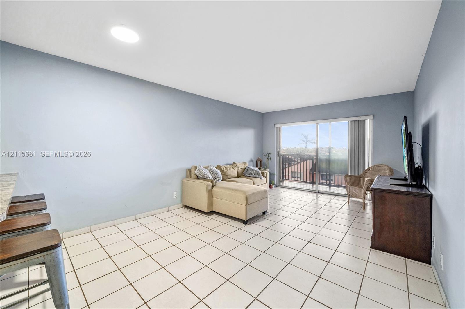 Living space featuring light-colored tile flooring, recessed lighting, and a sliding glass door providing external access