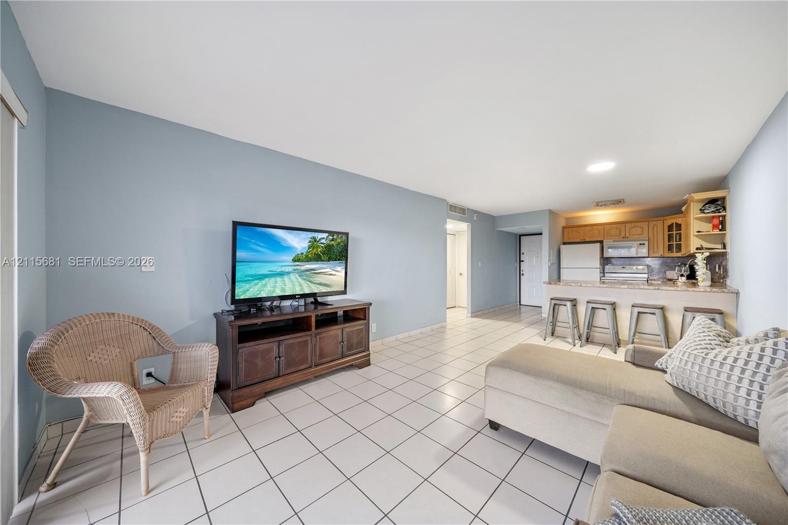 Open-concept floor plan featuring ceramic tile flooring, kitchen breakfast bar with stone-surface countertop, and recessed lighting