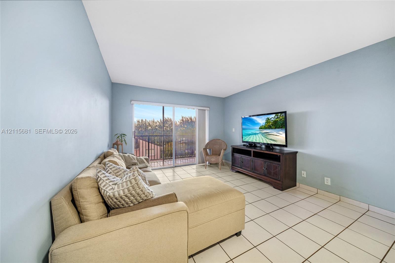 Living area featuring tile flooring and sliding glass doors with access to an exterior balcony