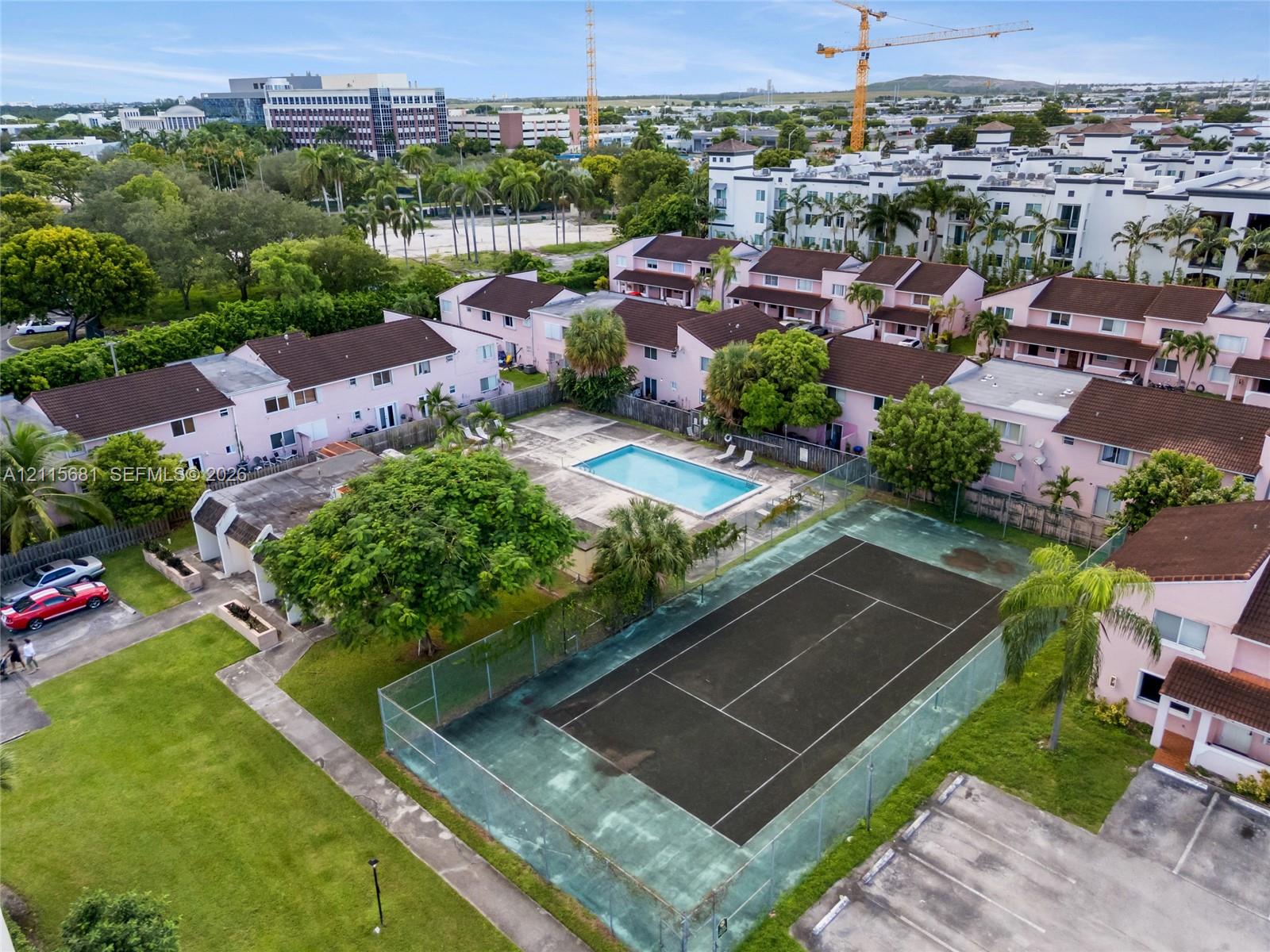 Community amenities including a swimming pool, fenced tennis court, paved parking area, and manicured green spaces