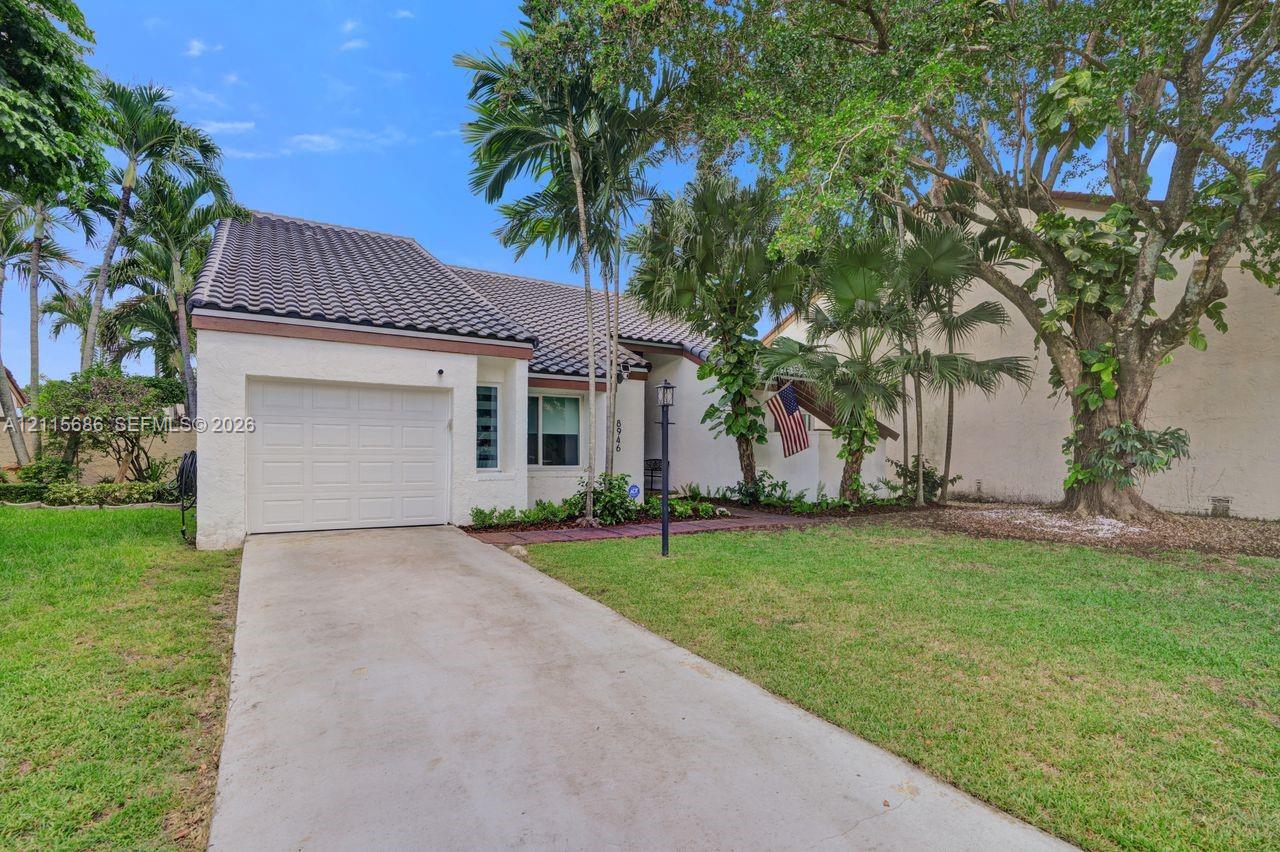 Stucco exterior with a tiled roof, single-car garage, concrete driveway, and mature landscaping