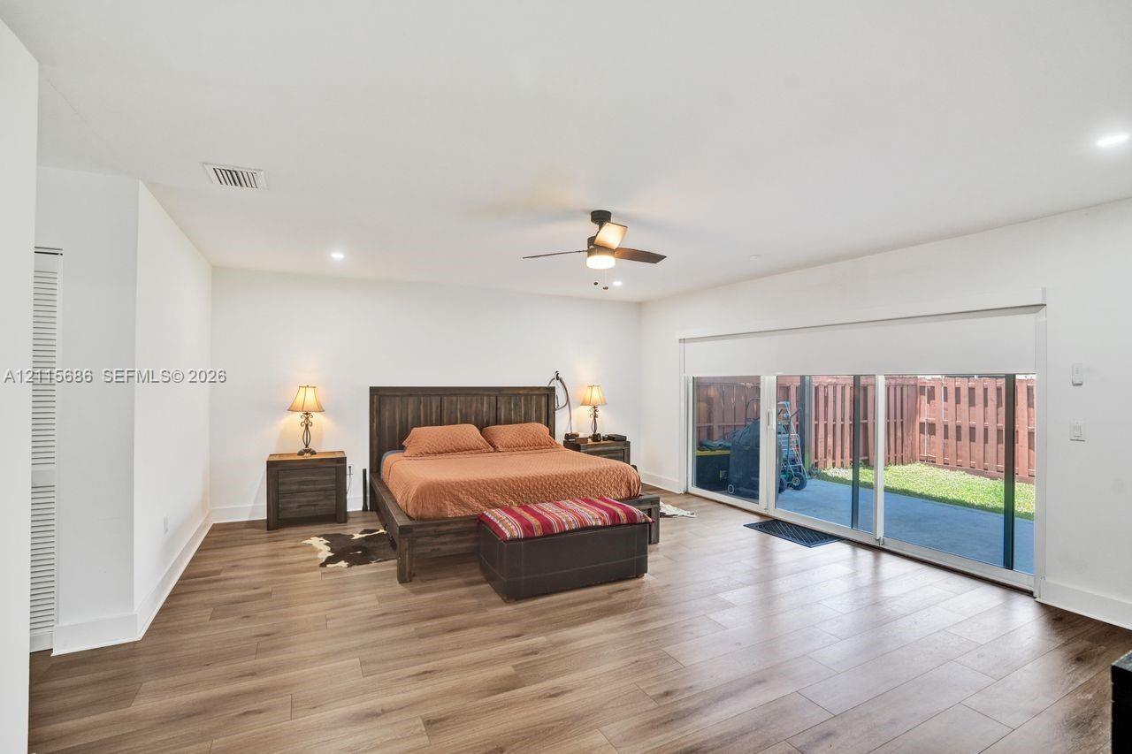 Wood-finish flooring, recessed lighting, ceiling fan with integrated light fixture, and sliding glass doors with roll-down shades
