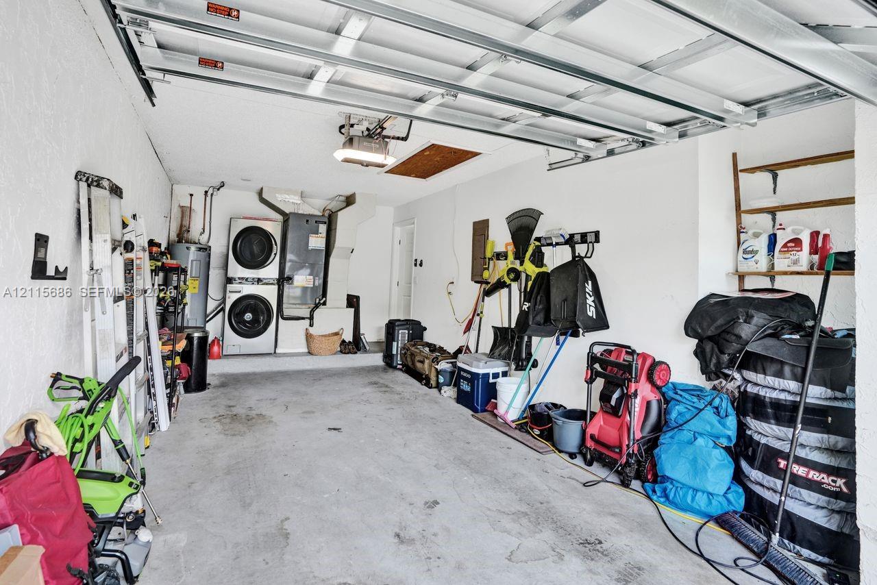Garage interior featuring concrete flooring, an overhead sectional garage door mechanism, and a dedicated laundry area with stacked appliance hookups