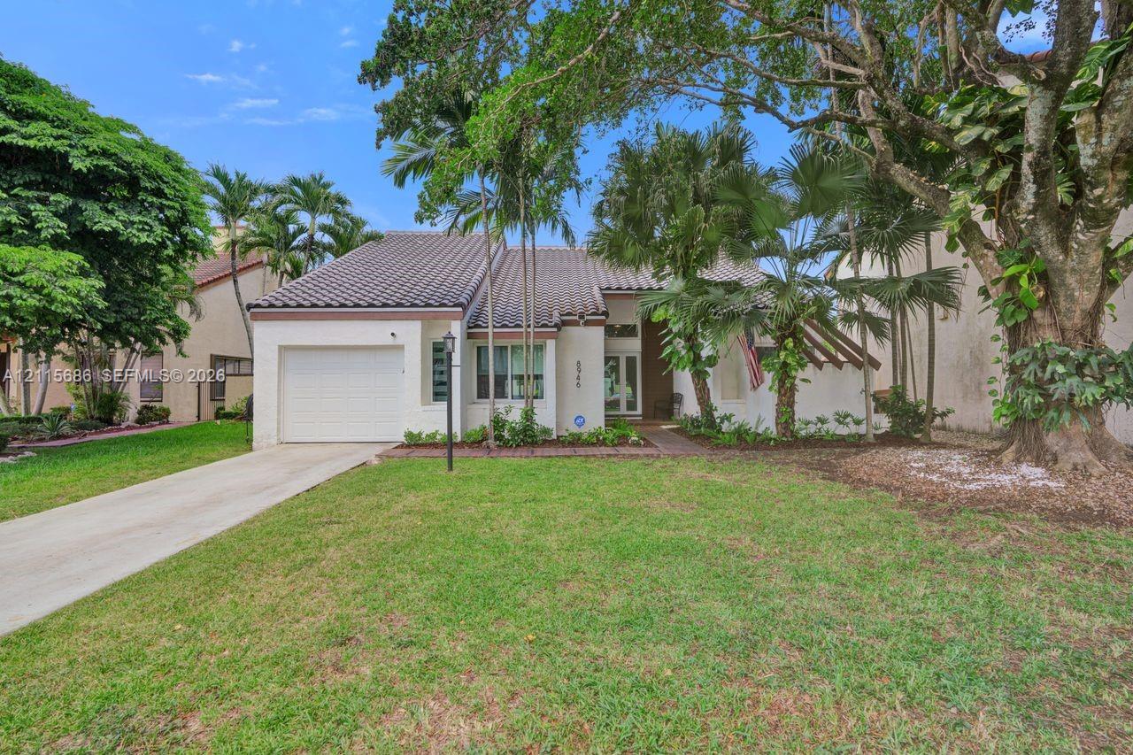 Single-story exterior featuring a tile roof, stucco siding, an attached garage, and mature landscaping