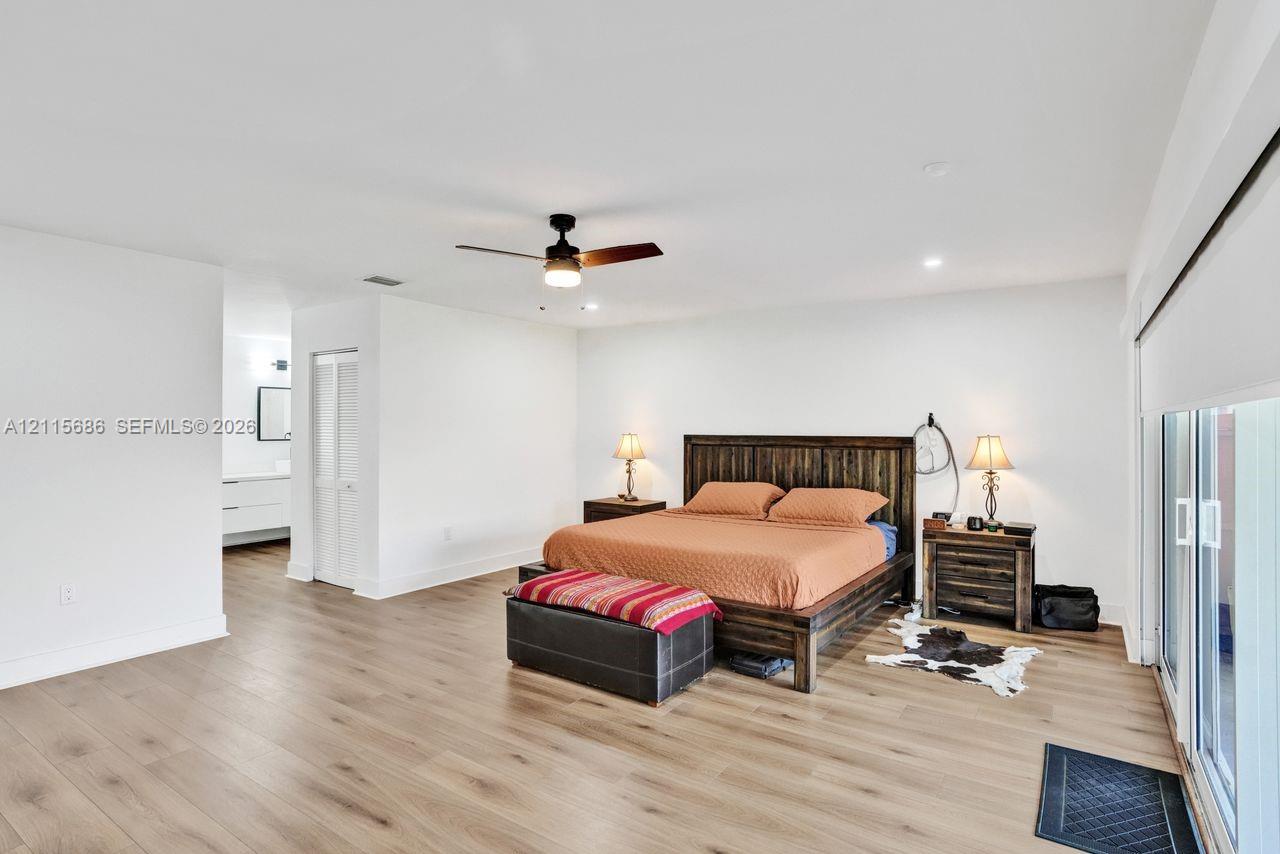 Neutral interior featuring wood-finish flooring, a ceiling fan with integrated lighting, recessed ceiling lights, and sliding glass doors