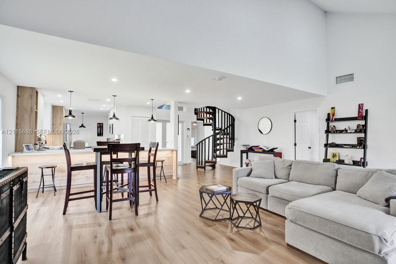 Vaulted ceilings, open-concept floor plan, spiral staircase, wood-finish flooring, and kitchen island with integrated lighting