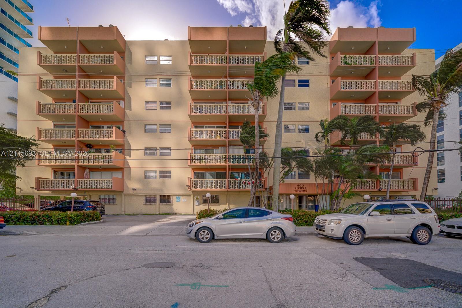 Multi-story exterior facade featuring recessed private balconies, decorative masonry screens, and on-site surface parking